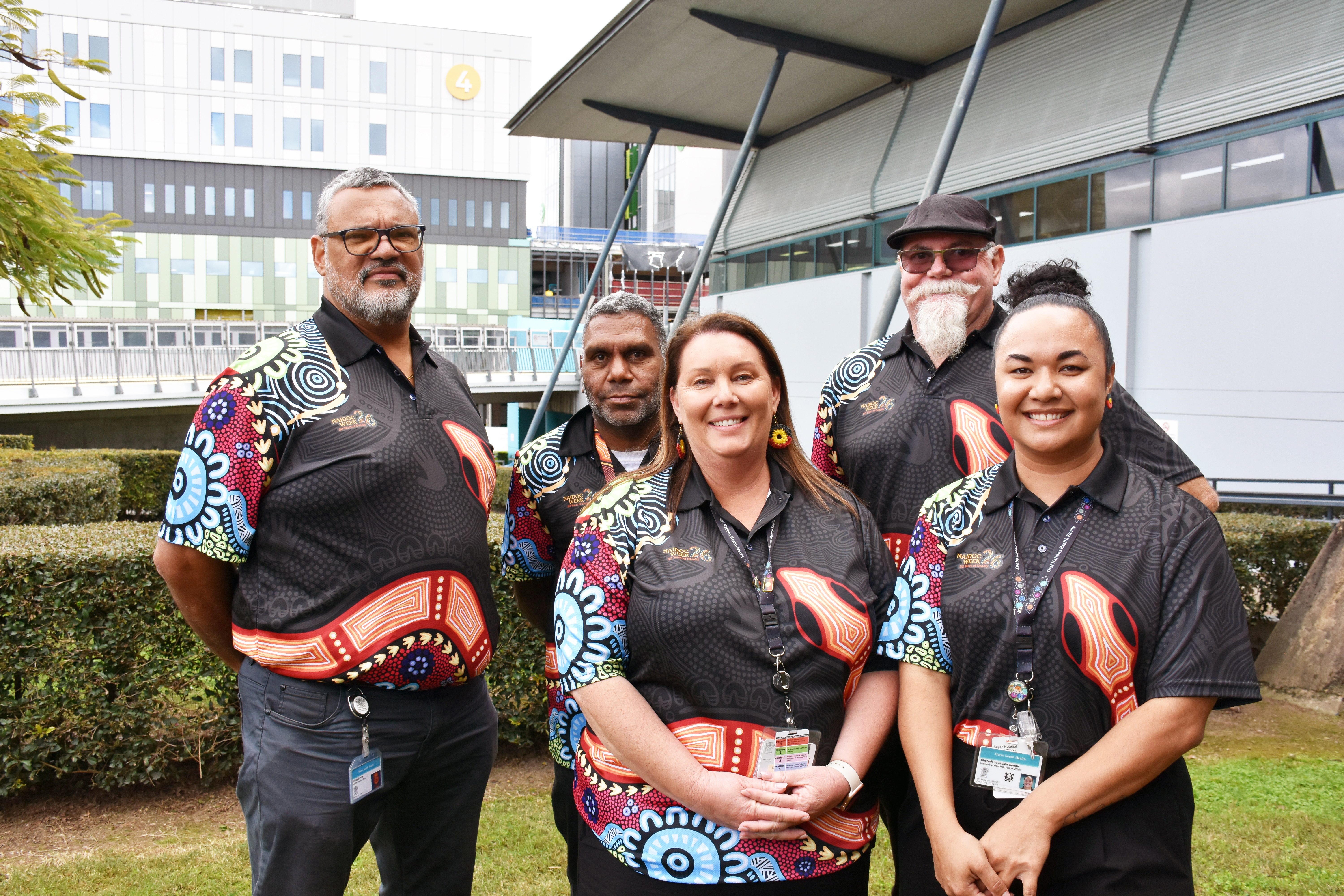 a group of First Nations workers dressed in black shirts with Indigenous artwork