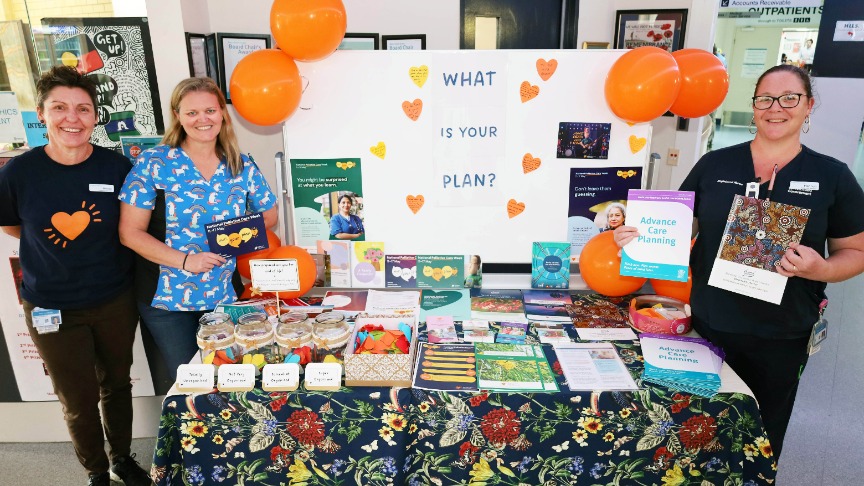 3 Palliative Care nurses standing next to display table