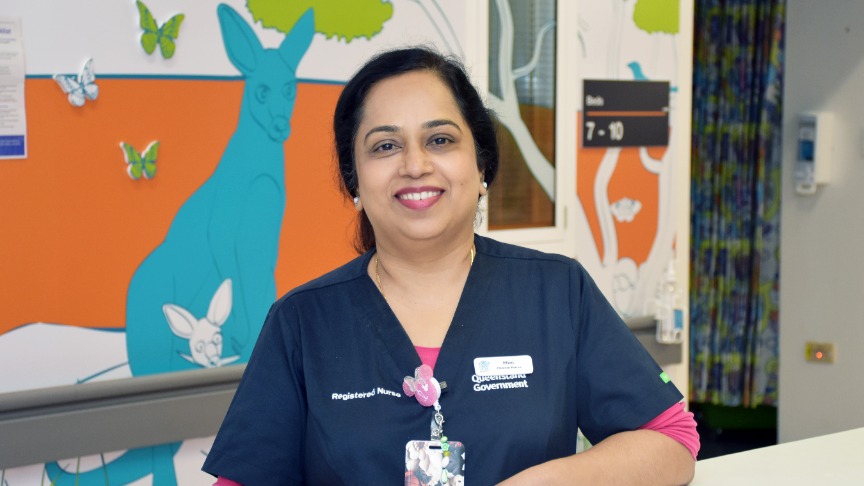 female nurse standing in front of a brightly coloured wall
