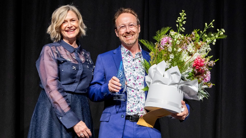 Female executive and male doctor on a stage with a flower bouquet