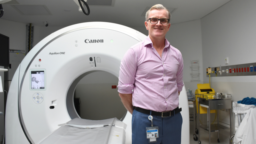 Michael Neep standing in front of a CT machine