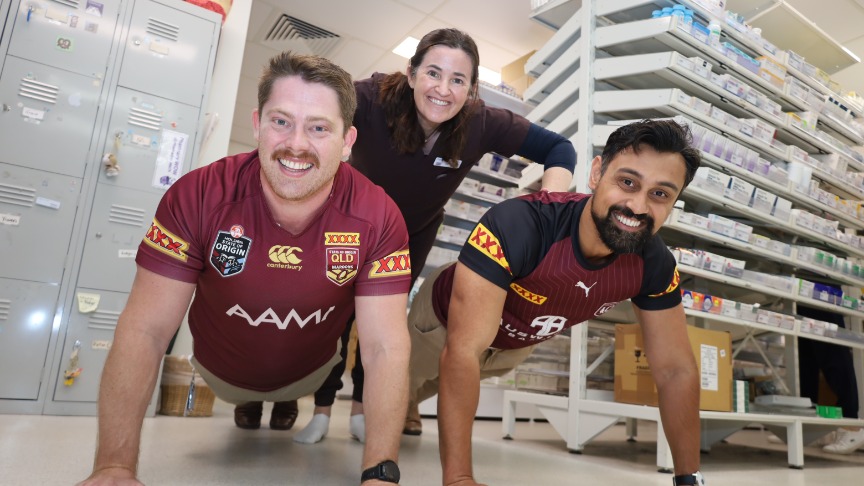 3 staff members form a push-up pyramid in QEII Pharmacy