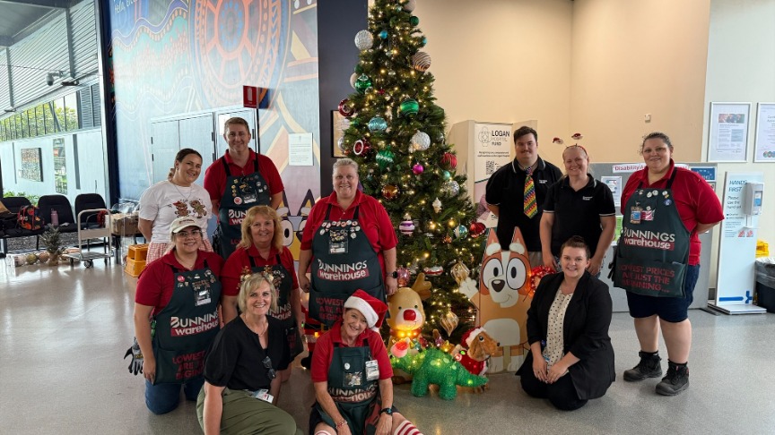 Group of people standing and sitting in front of a Christmas tree