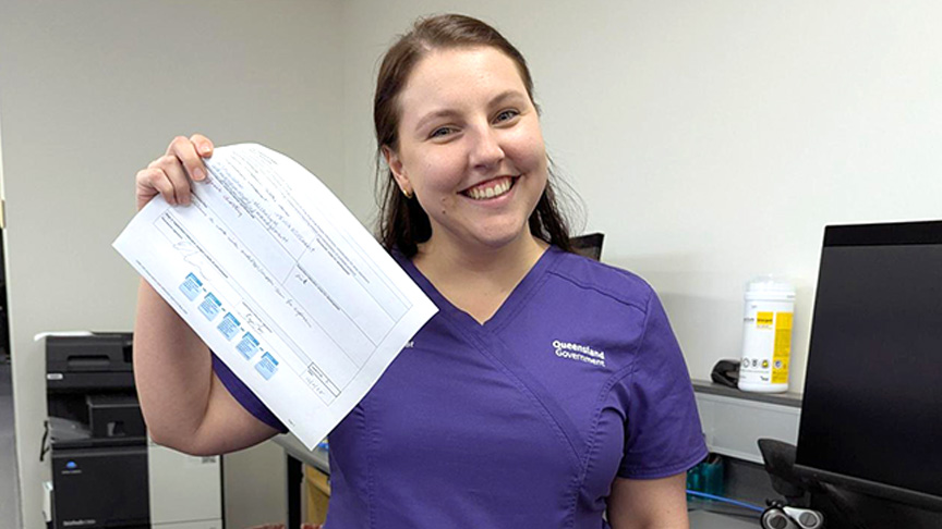Pharmacist in purple scrubs holding up a piece of paper
