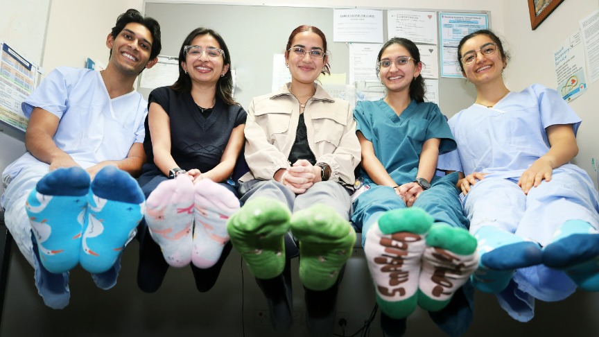 A group of doctors sitting on a bench, celebrating Socks 4 Docs Day with colorful socks and cheerful expressions
