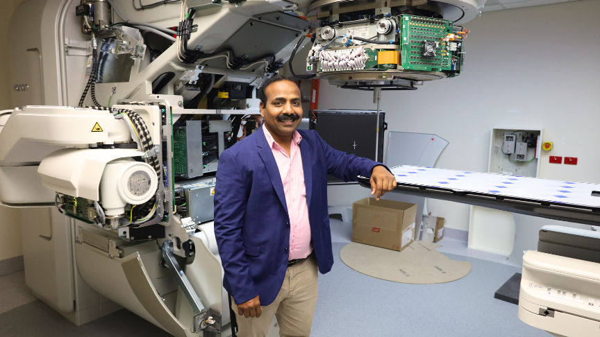 Dr. Prabhakar Ramachandran stading in front of a linear accelerator