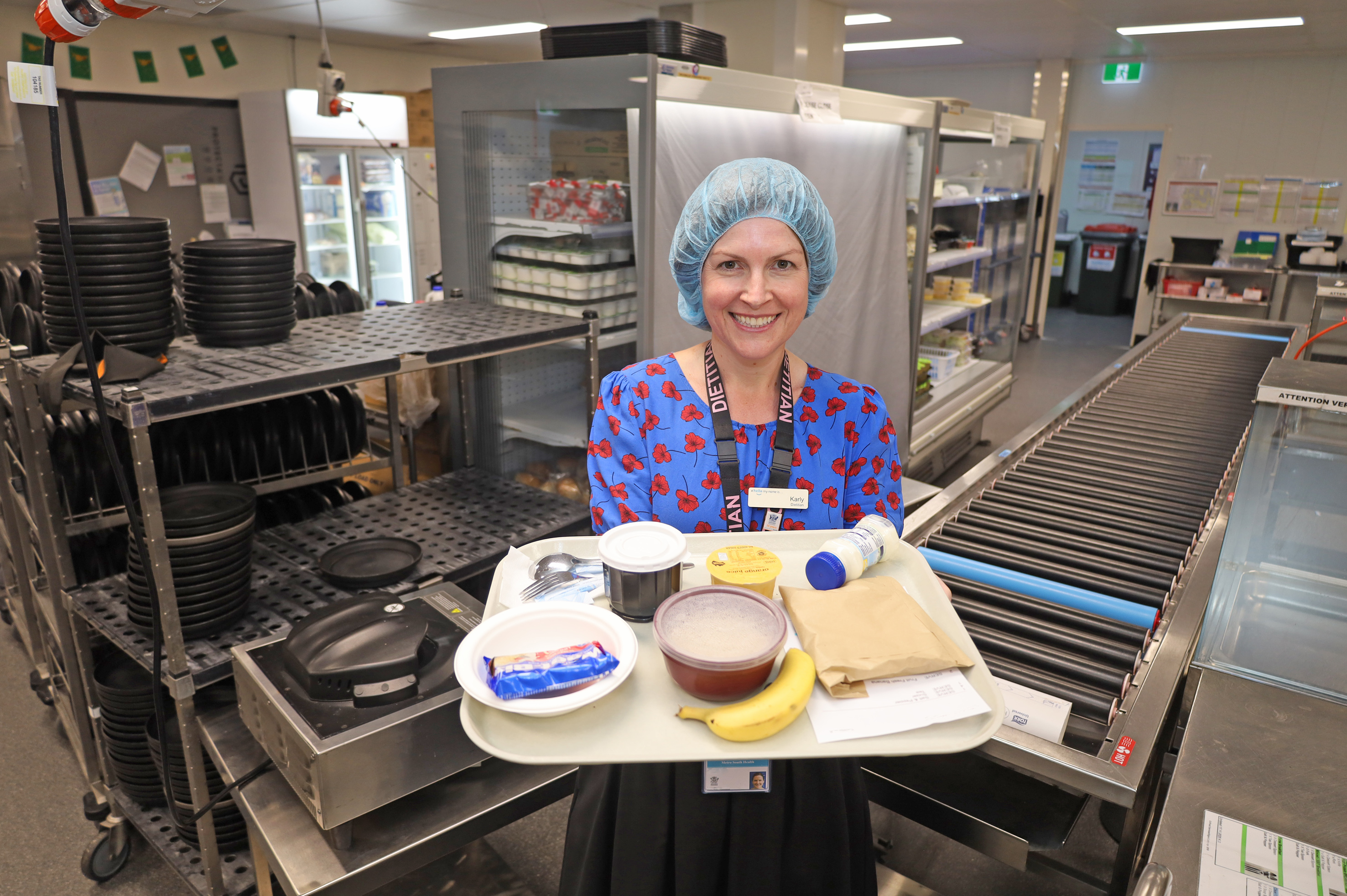 Karly Miller smiling with a plate of food in the kitchen at QEII Hospital.
