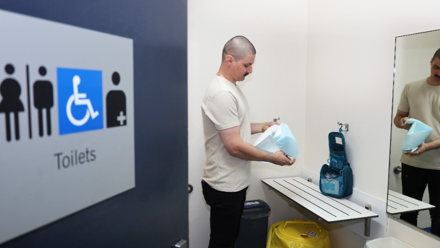 A man stands inside the new ostomy-friendly toilet at PA Hospital, showcasing its accessibility features