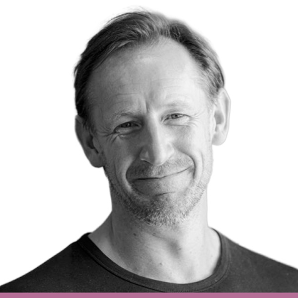 Black and white image of a person with short hair, shown from the shoulders up wearing a tshirt against a white background