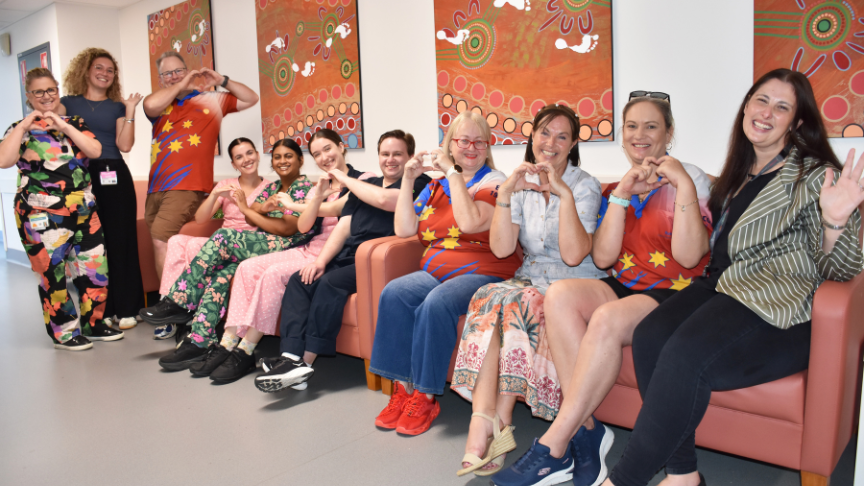 large group of mixed gender staff sitting on burnt orange sofas