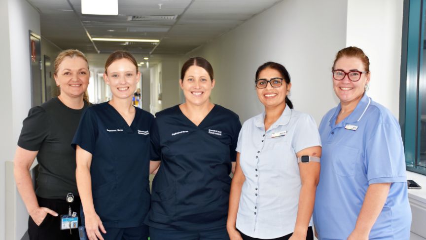 group of five nurses standing in a hallway