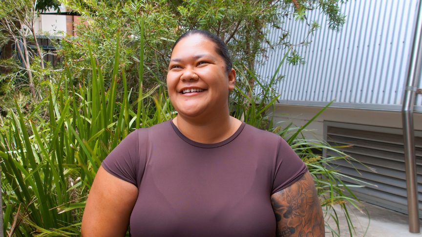 A woman smiles with a lush green garden in the background.