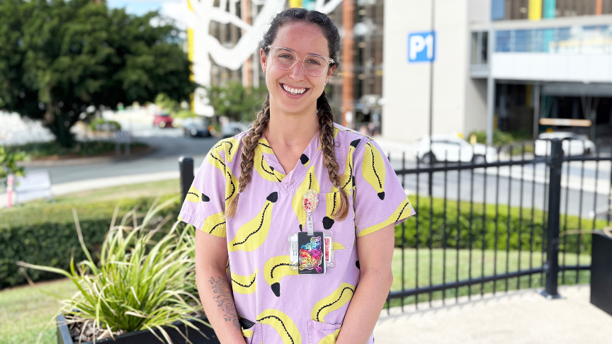Woman in bright coloured scrubs standing outside