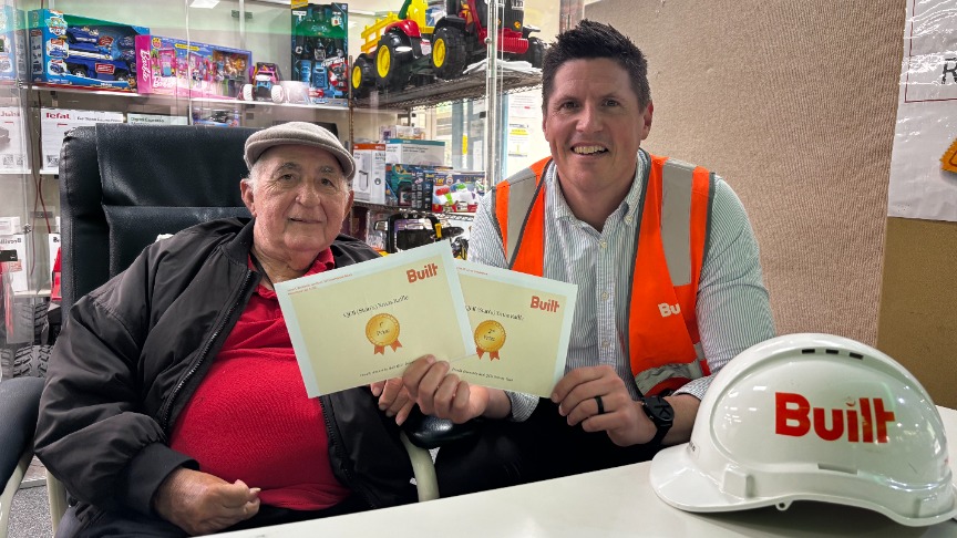 two men sitting at a desk holding vouchers