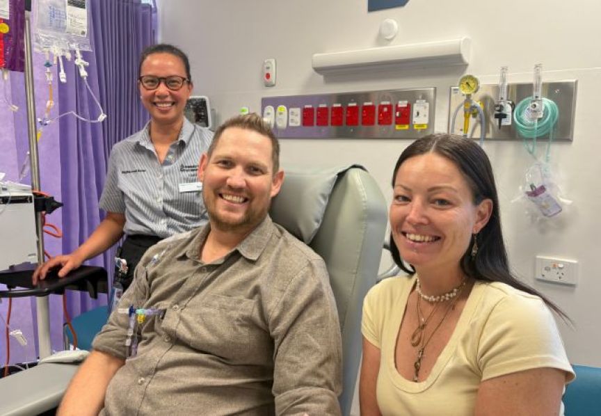  In a hospital room, a patient lies in bed with two supportive individuals seated beside them, fostering a caring environment.
