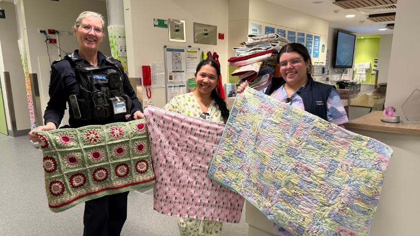 Police officer and two nurses standing with a blanket donation