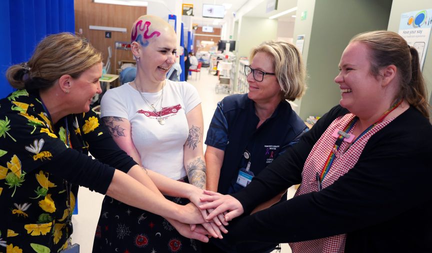 A group of women, including youth cancer patient Kirsty, putting their hands in, in a hospital setting
