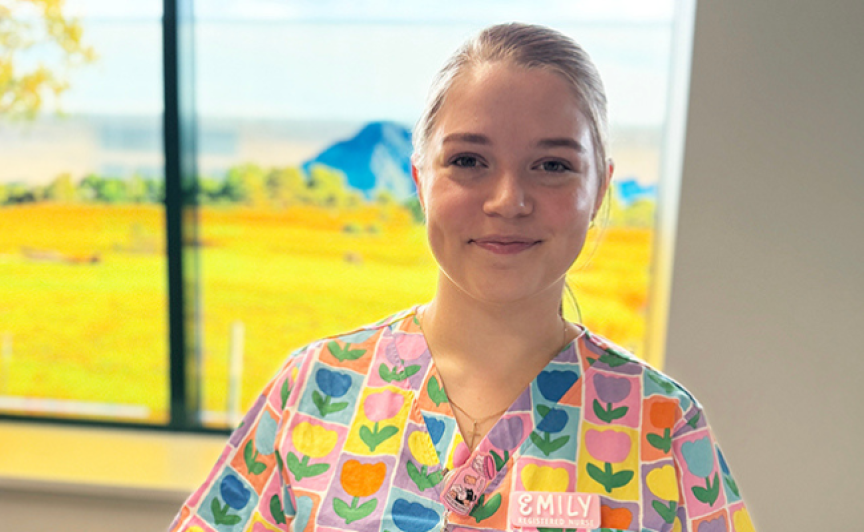 A nurse in colourful scrubs smiles