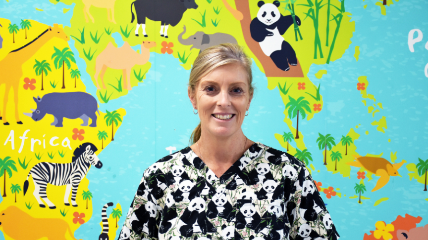 Headshot of a female standing in front of a bright map of the world decal