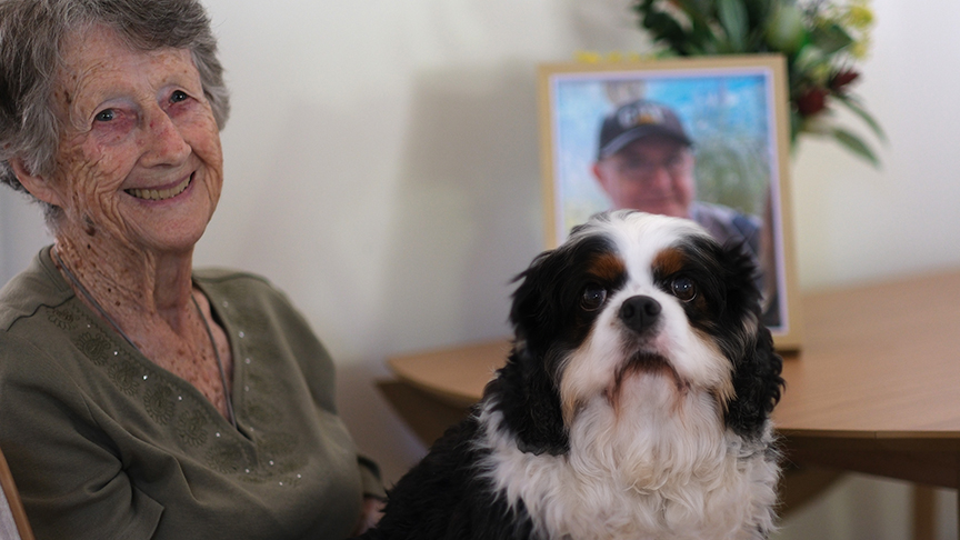 An older woman sitting down and holding a dog