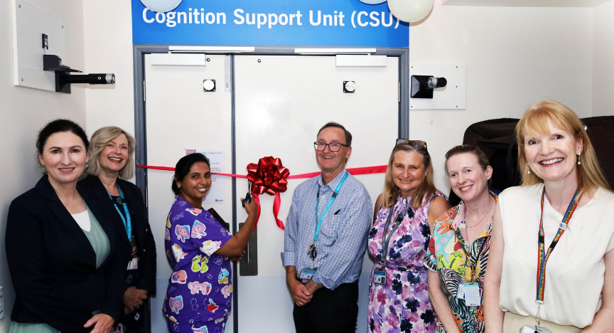 PA Hospital staff celebrate the opening of the Cognition Support Unit, gathered in front of a door adorned with a ribbon
