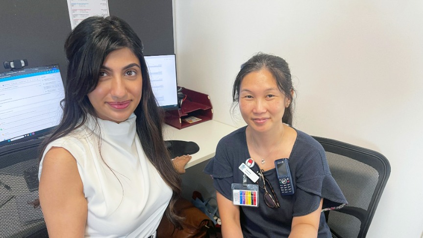 Two women pharmacists at Logan Hospital sit at a desk, reviewing papers and discussing patient care