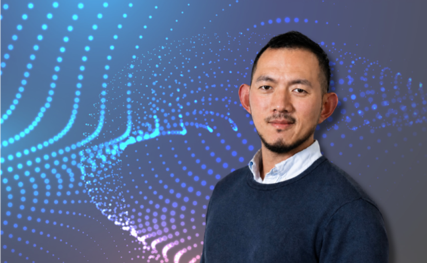 Headshot of a male nurse in business attire in front of a patterned graphic background