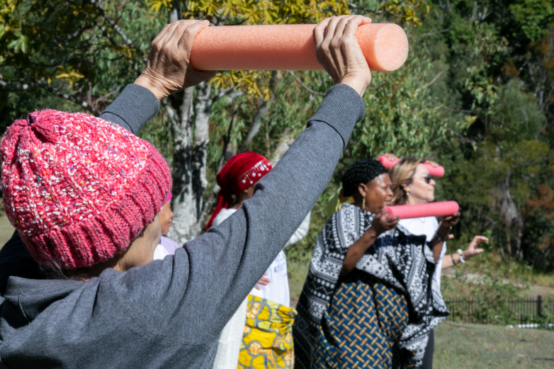 A multicultural group of people doing gentle physical activity in a park 