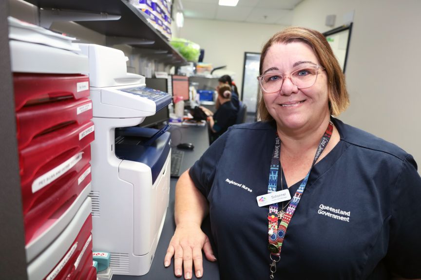 A female nurse leader standing in a clinic smiling at the camera