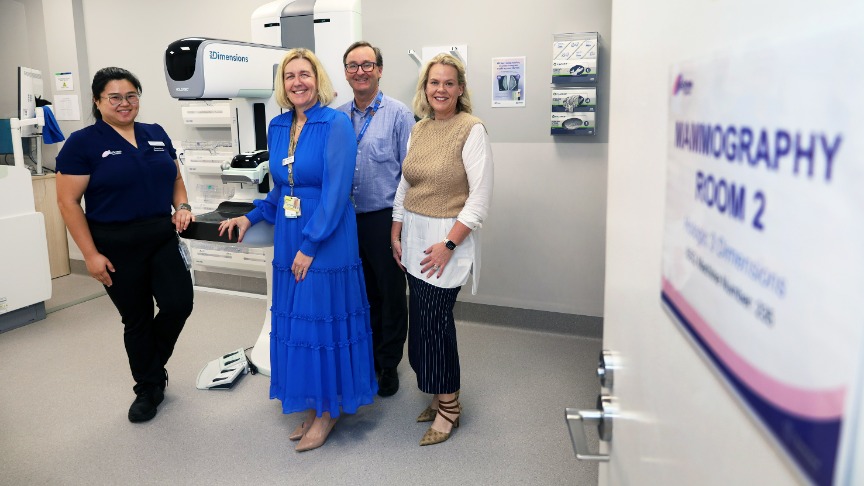 A female radiographer standing by a mammography machine with a female service manager, a male hospital executive and a female Queensland Health Service leader at the new BreastScreen Coorparoo facility