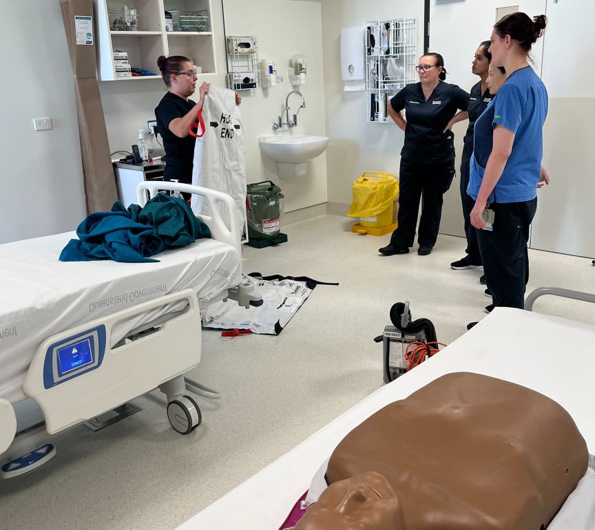 A dummy in the foreground with nurses training in the background