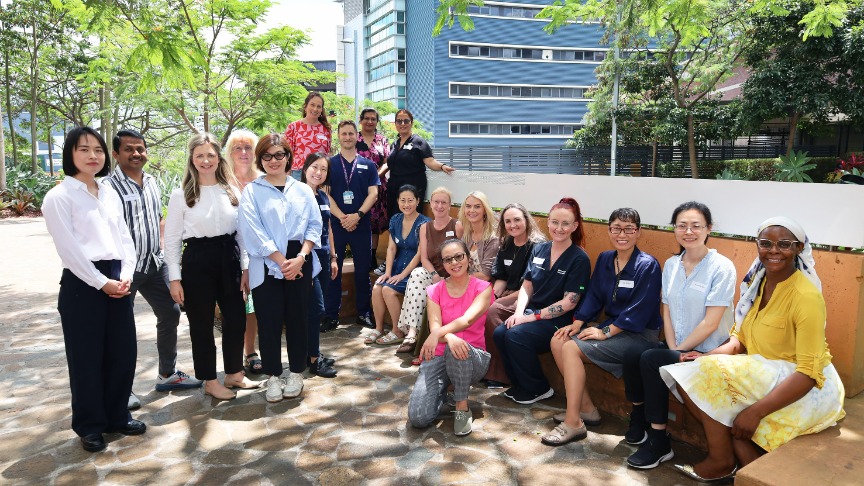 A group of 20 experienced female and male nurses with practitioner credentials standing and seated in an outdoor courtyard at PA Hospital