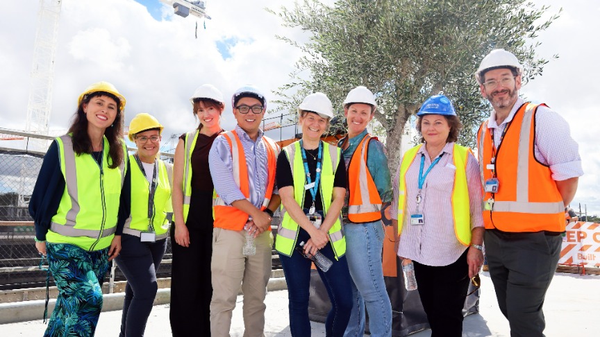 A group of Metro South Health staff in hard hats and high-visibility vests at a construction site