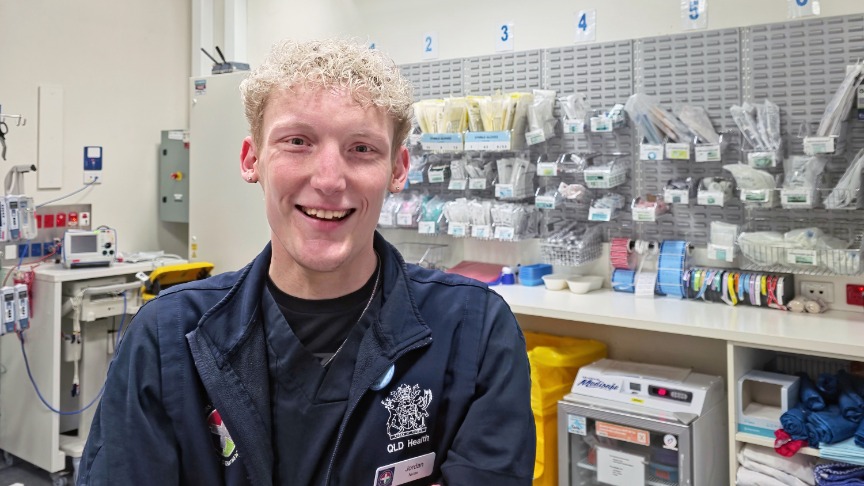 A male nurse smiling at the camera in an emergency resuscitation room