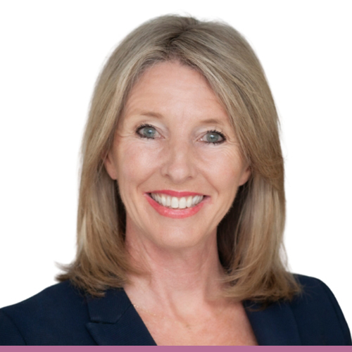 A person with shoulder length sandy blonde hair, wearing a navy blazer