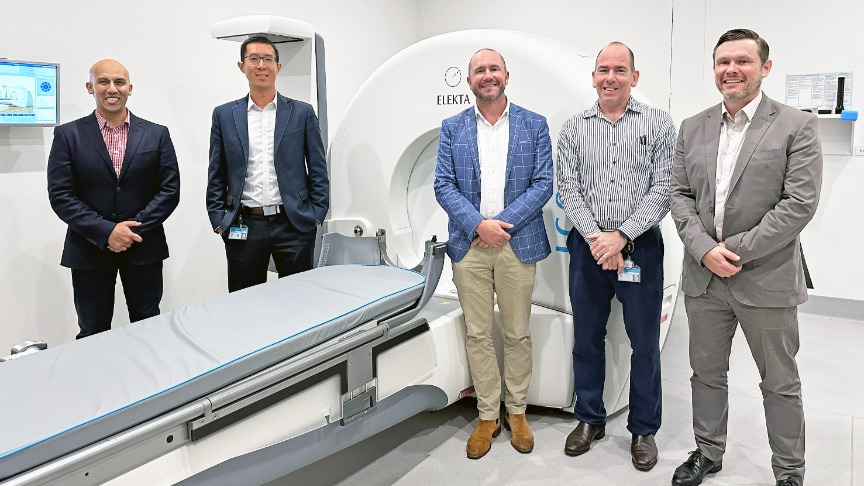Radiation Oncology clinicians standing alongside a specialised cutting-edge radiation machine in a hospital treatment space