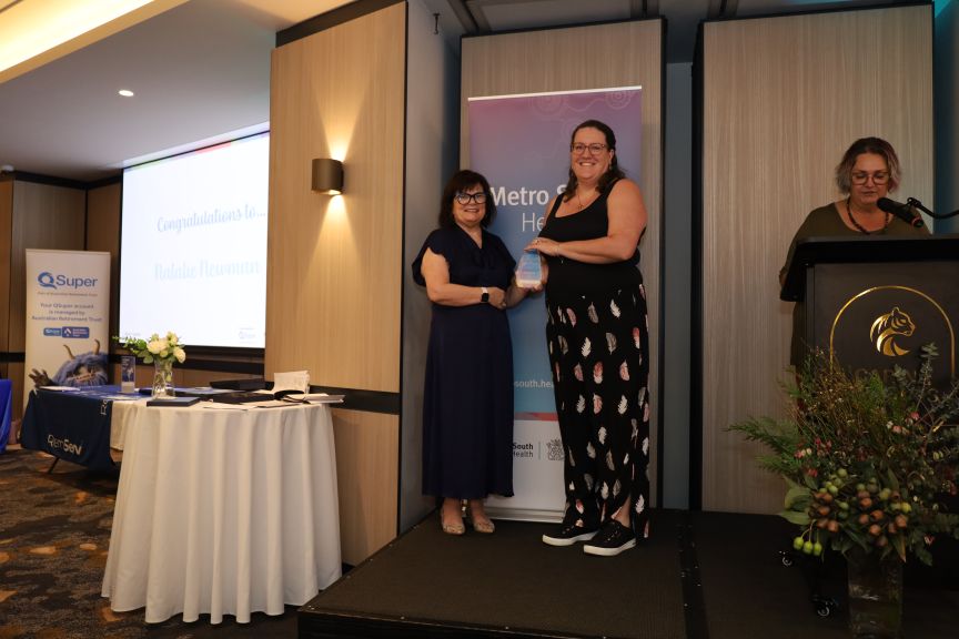 A woman receiving an award from another woman in an event space